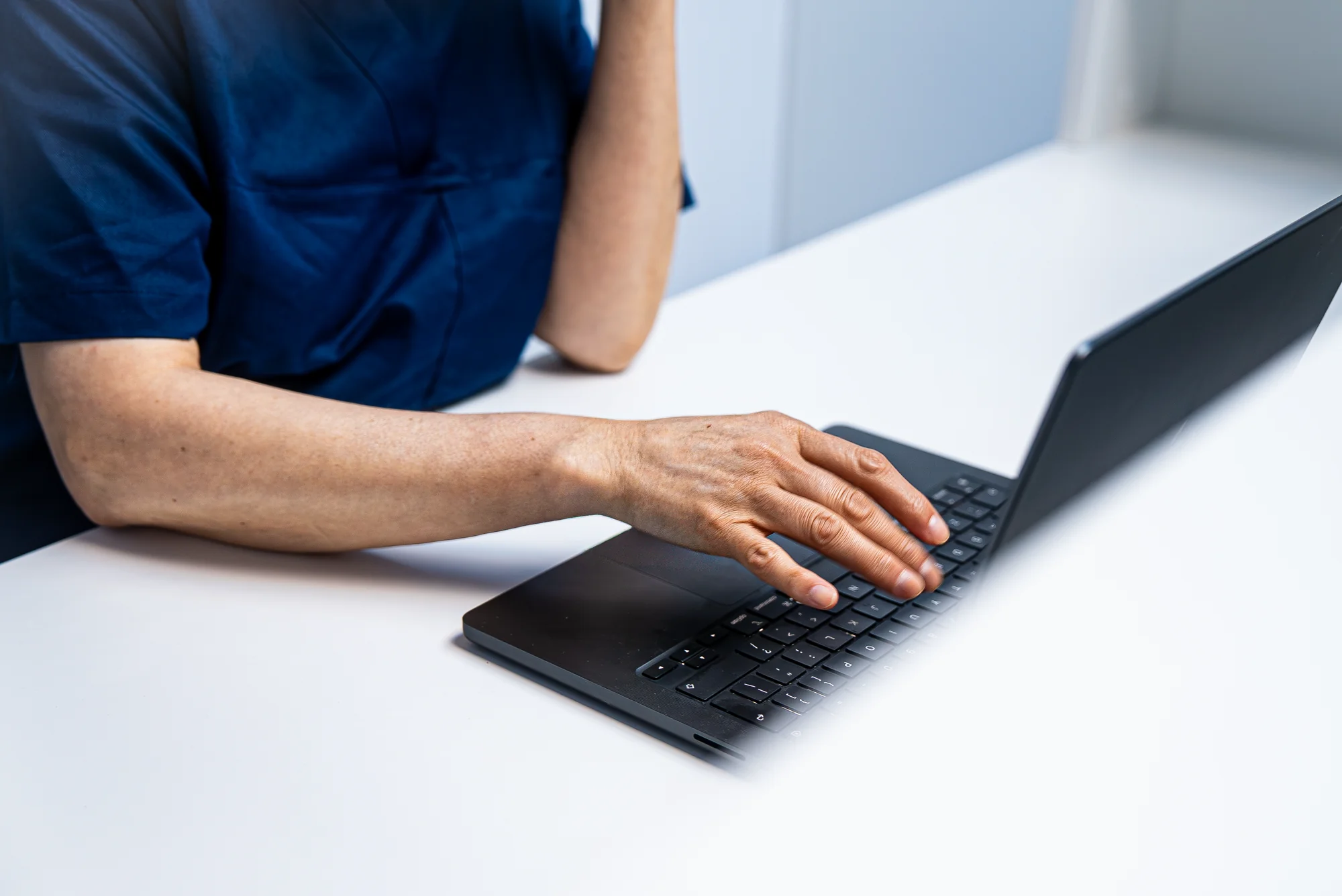 Hand op het toetsenbord van een laptop aan de balie
