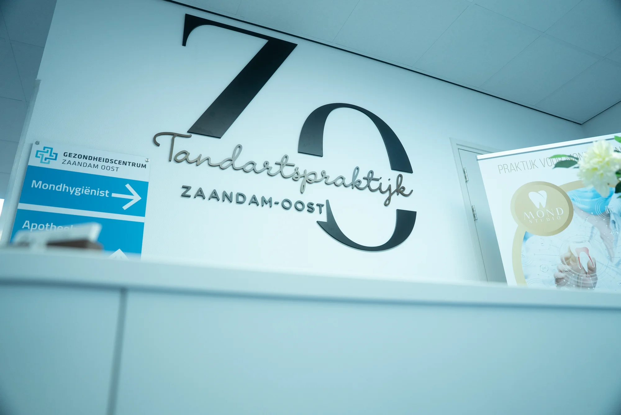 Logo van Tandartspraktijk Zaandam-Oost op de muur, met een bord naar de mondhygiënist